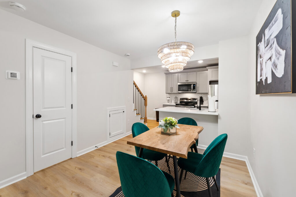 Dining area with green velvet chairs and the kitchen beyond